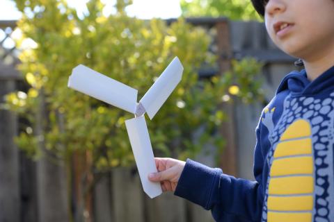 Child holding a 3 prong boomerang. Boomerang is made by child