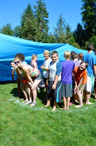 kids standing next to a large blue tarp. 