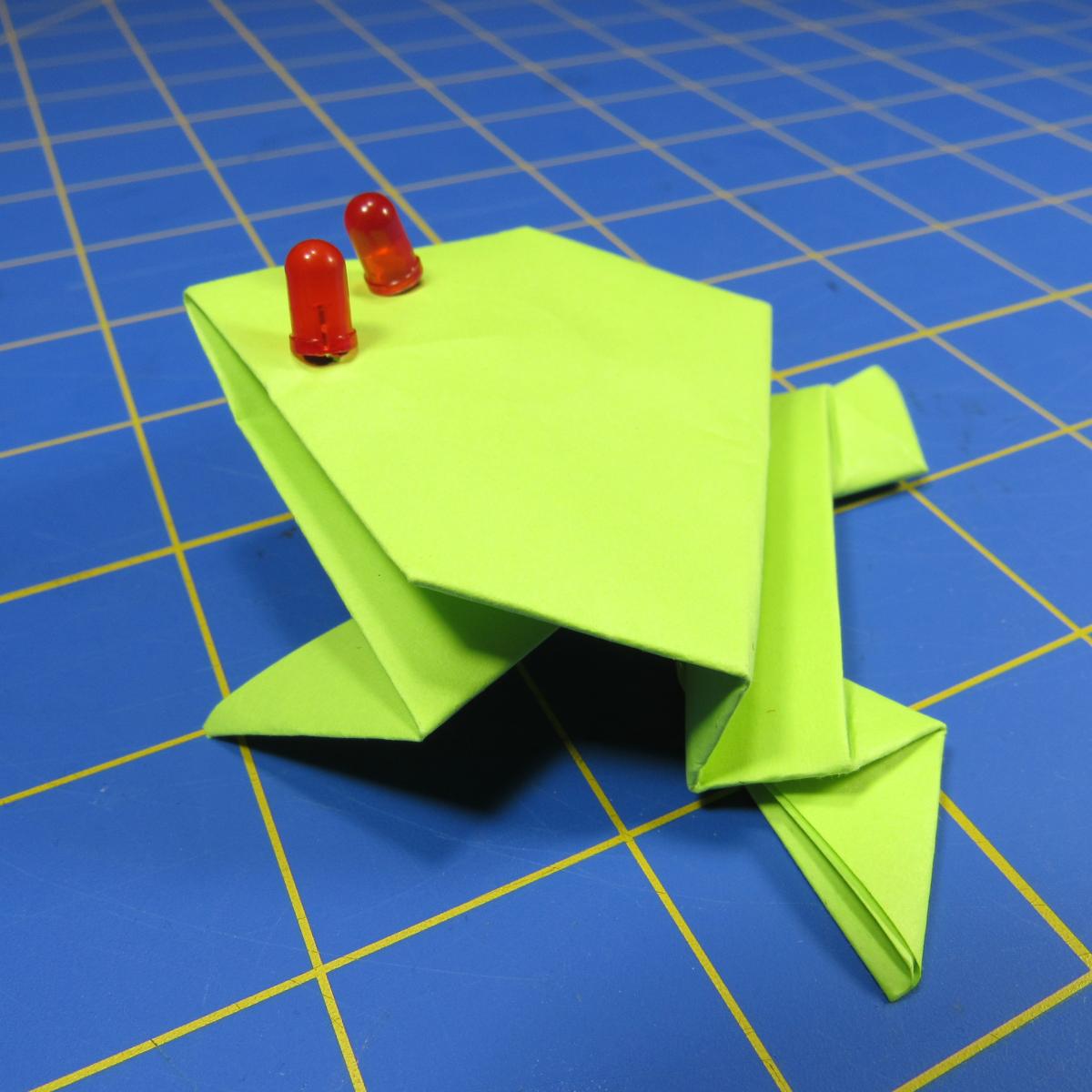 Green origami frog with LED red eyes